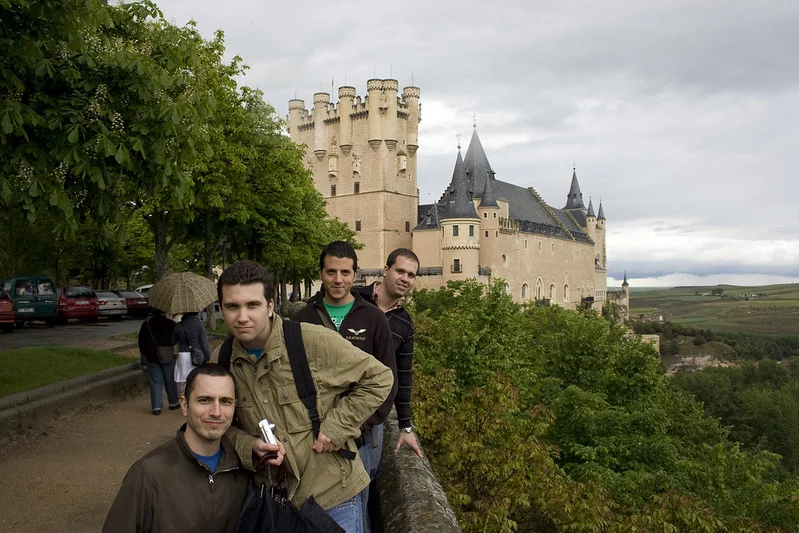 A group of four tourists taking picture in front of the Segovia castle on a cloudy day.