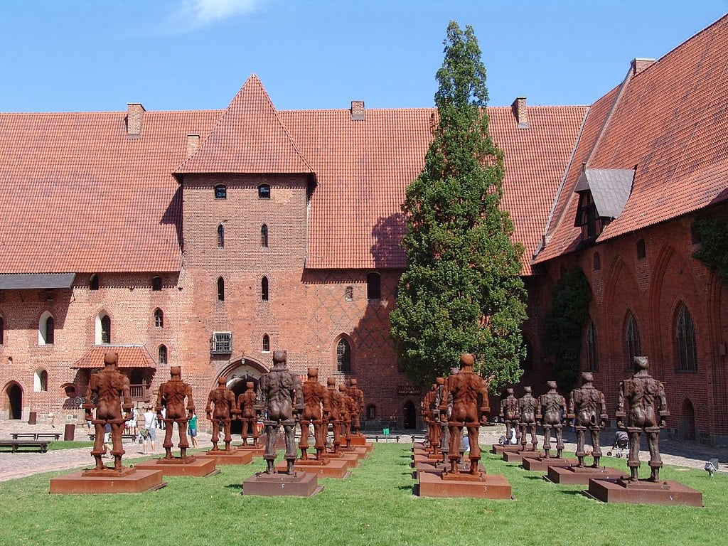 Courtyard of Malbork Castle with multiple metal sculptures of the knights of Teutonic Order