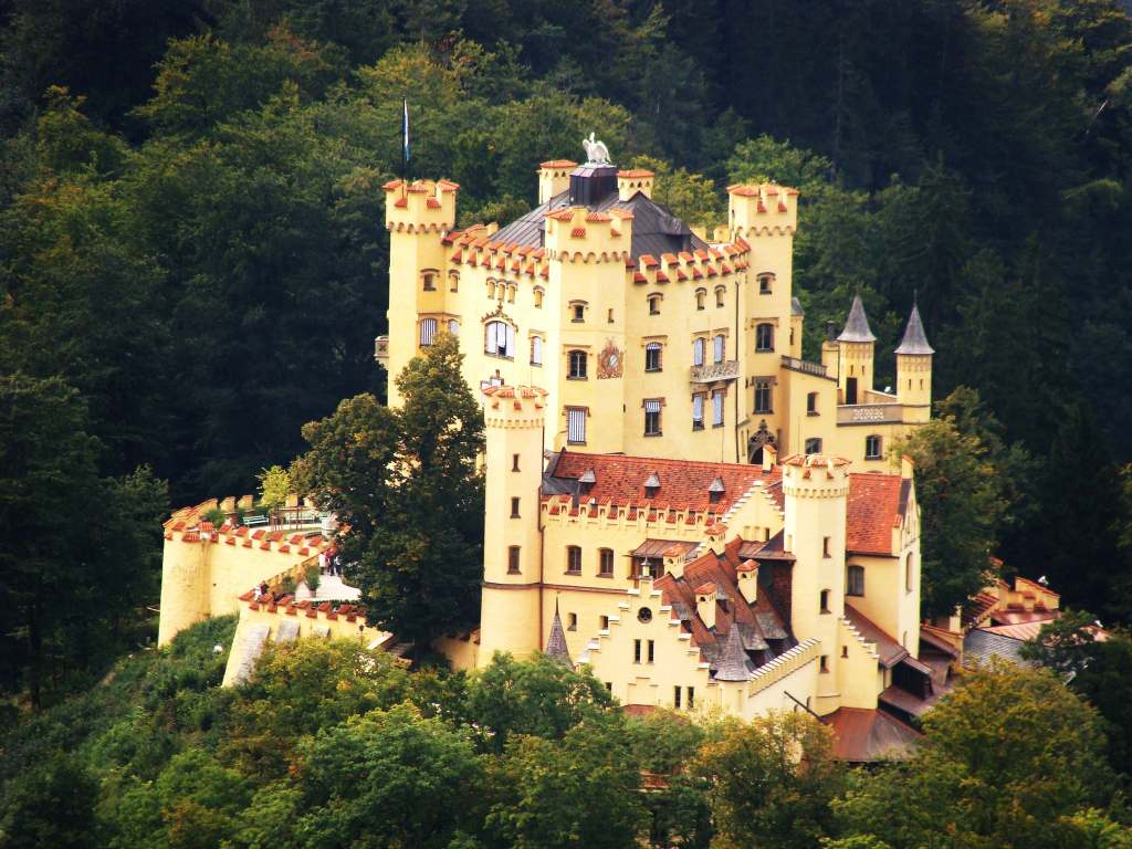 An aerial view of the Hohenschwangau castle with its forestry green surroundings 