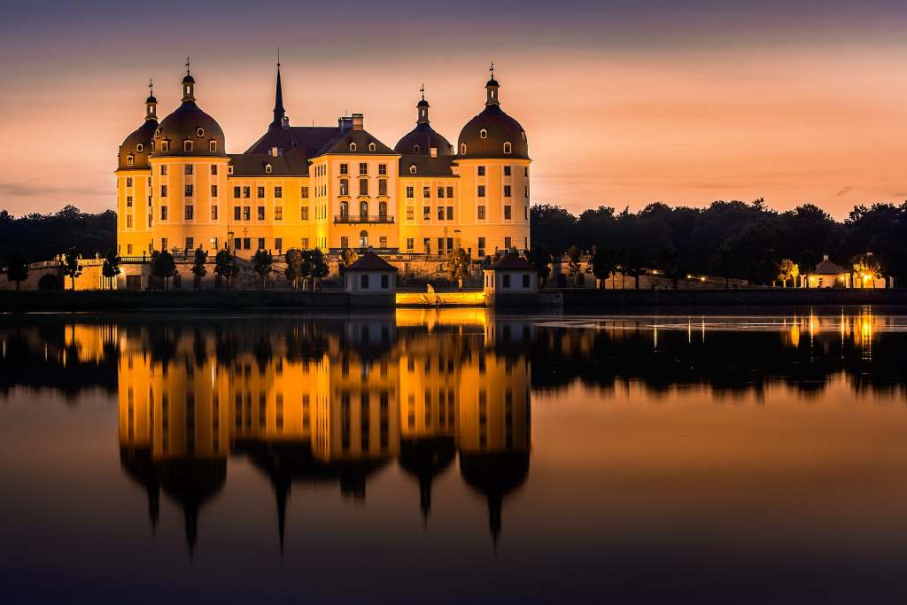 moritzburg castle from a far reflecting on the surface on the lake in the nigh