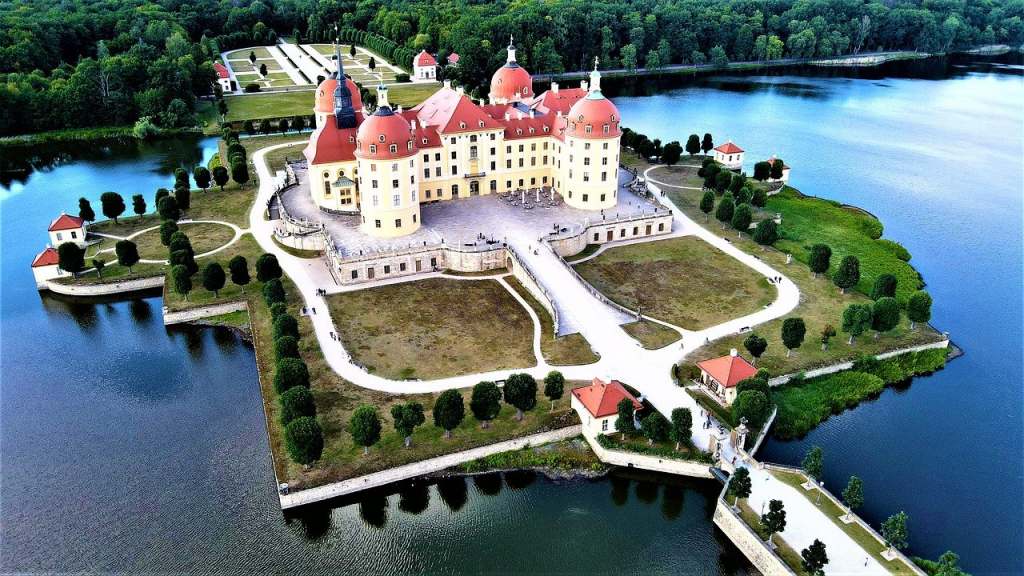 Beautiful aerial drone shot of Moritzburg castle and its perfectly shaped island surrounded by the lake moat, trees and the bridge.