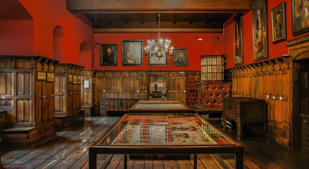 The interior of the Altena Castle museum in front view with red wall and paintings.