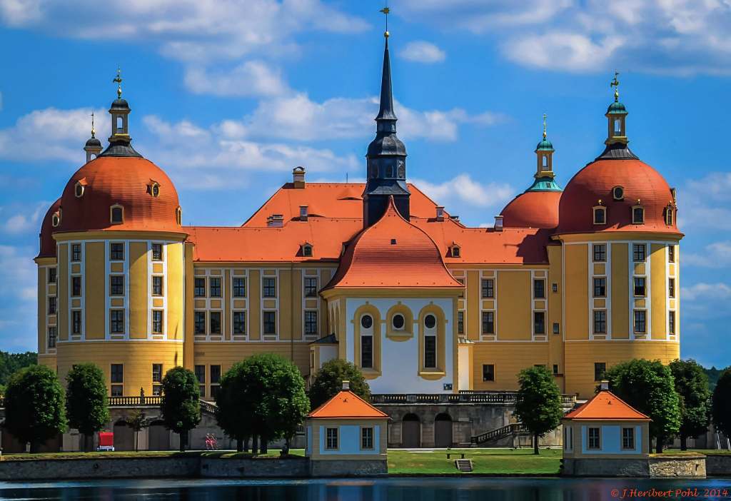 The dramatic baroque-style architecture of the Moritzburg castle with red rooftops in the sunlight.