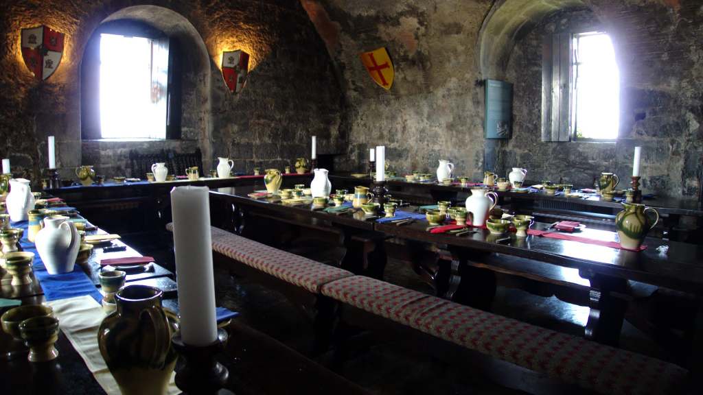 The banquet hall in Dunguaire Castle with candles goblets and porcelain pitchers.