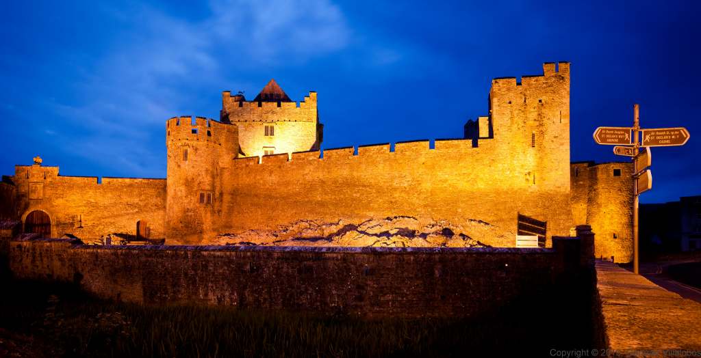 Cahir Castle's main entrance view at night with lights on.