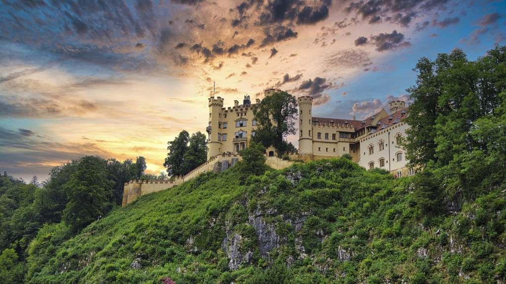 hohenschwangau castle from far away on a steep green hill