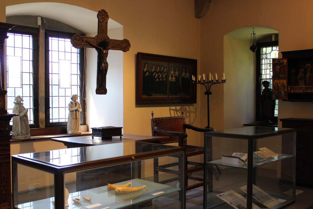 The inside of Altena Castle Museum where you can see a crucifix, books and statutes.