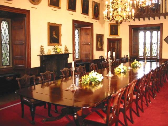 Malahide Castle's beautiful great hall with hanging portraits and chandelier.