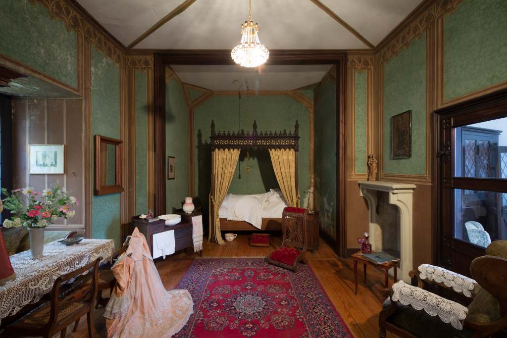 One of the elegant bedrooms at the Rheinstein castle with green wallpaper and a chandelier.