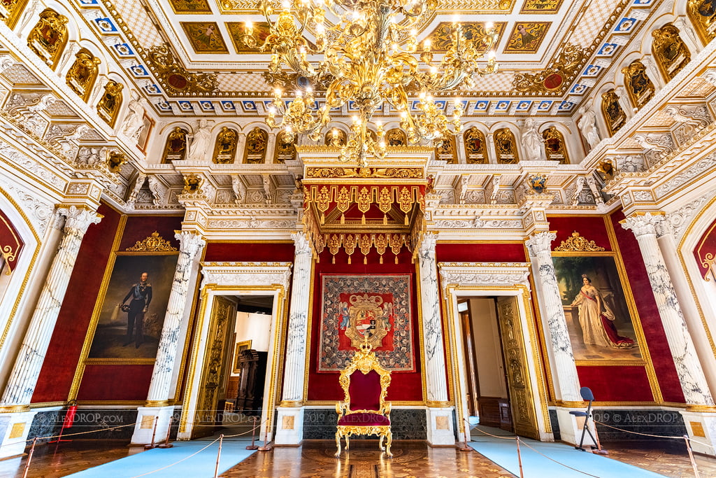 Magnificent Schwerin Castle red and gold accent throne hall interior view with a classy chandelier.