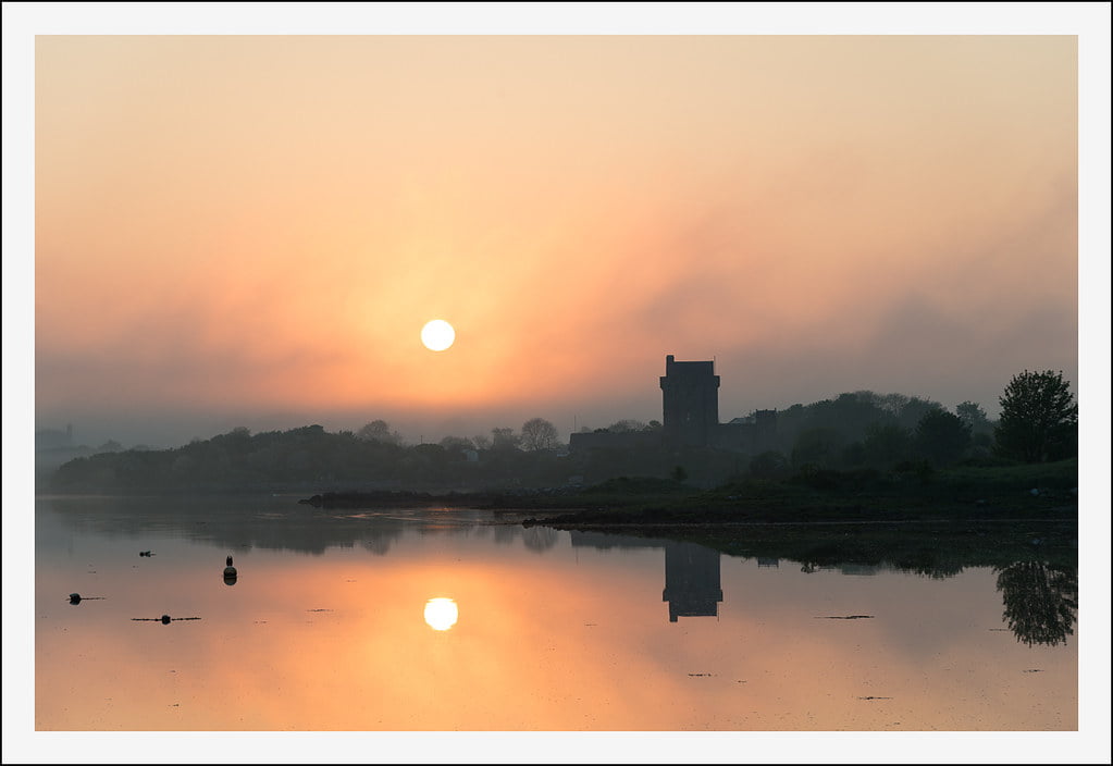 View of the beautiful sunrise at Dunguaire Castle beside the river.