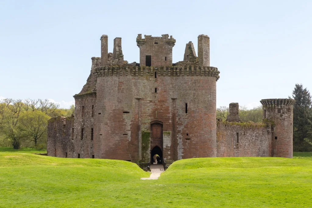 Caerlaverock Castle's entrance surrounded by green grasses.