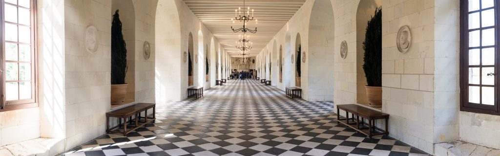 The panoramic view of Château de Chenonceau's hallway interior lined up with chandeliers