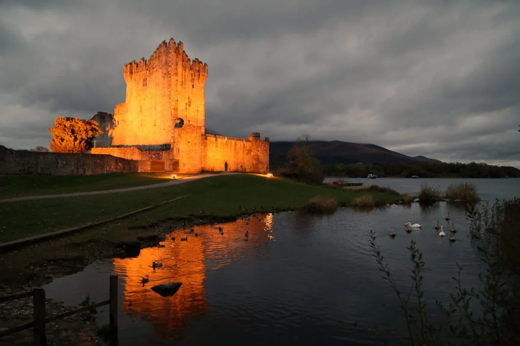 The stunning night view of Ross castle at the lakeside with the lights on.