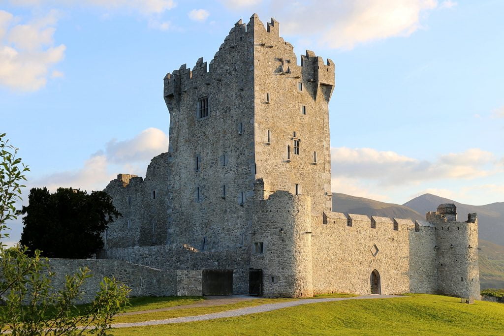 A side view of Ross Castle surrounded by green grass.