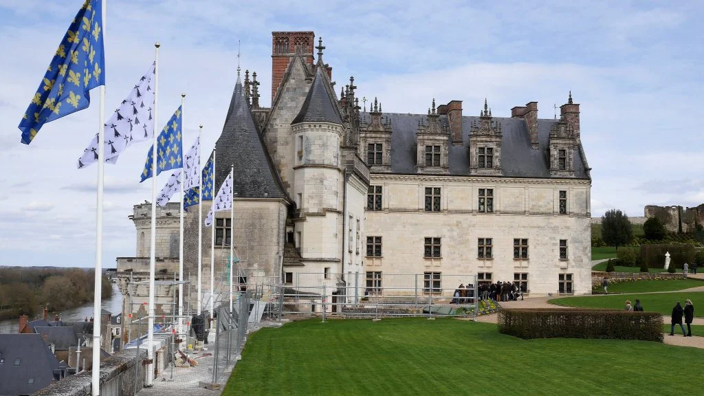 The side structure view of Chateau d'Amboise with the symbolic flag and its green surroundings.