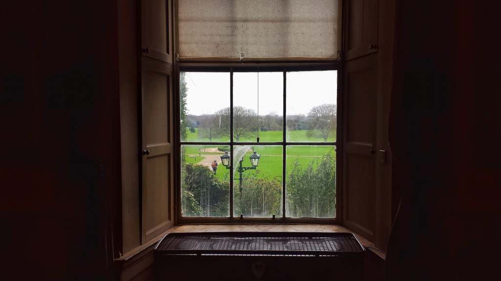 Interior window view of Malahide Castle where you can see the wide ground outside