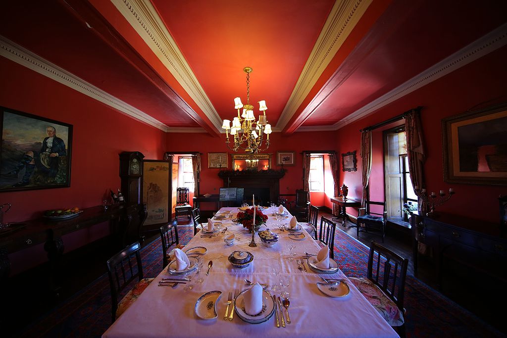 The elegant red dining hall at Braemar's Castle with plates and utensils displayed.