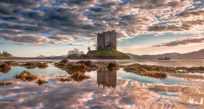 Castle Stalker from afar covered in beautiful pink and golden hues