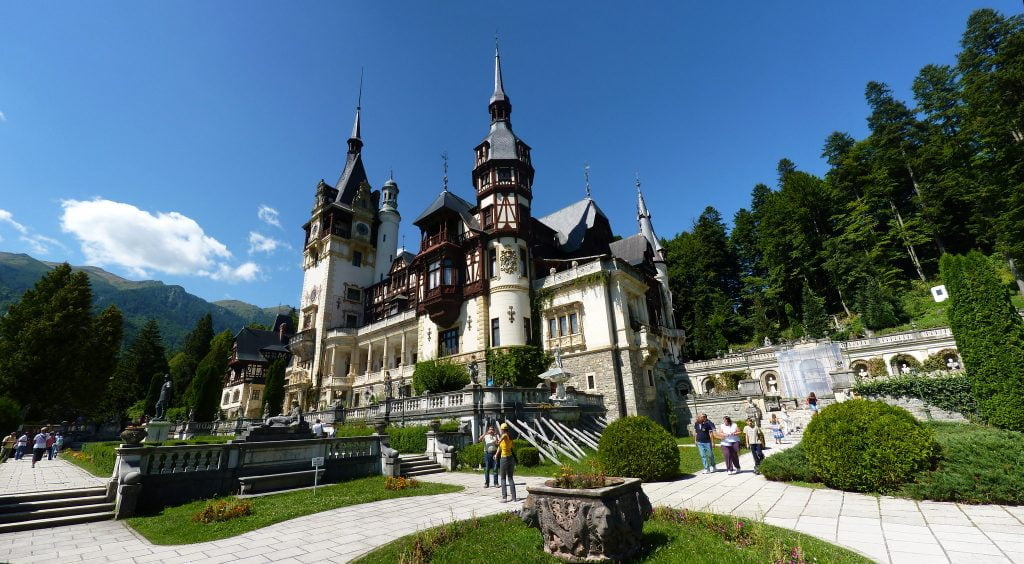 The panoramic view of Peles Castle surrounded by tourists.
