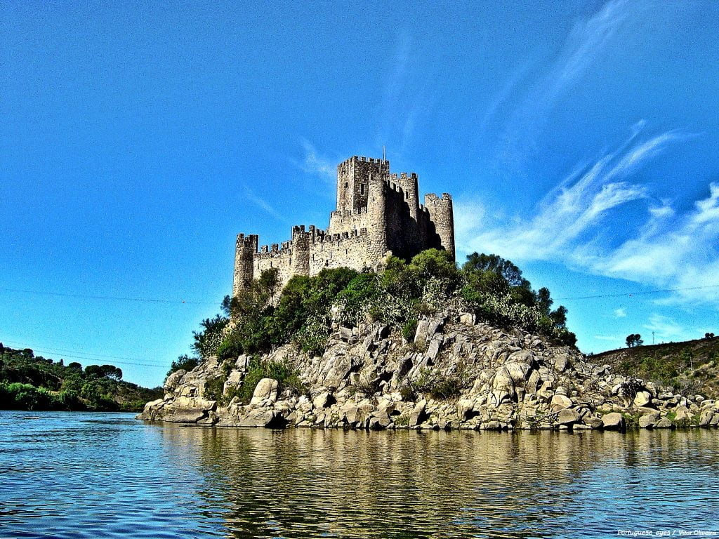The Castle of Almourol at the top of the hill surrounded by water.