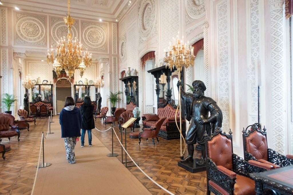 The classy interior of Pena Palace's hallway with gold chandeliers. 