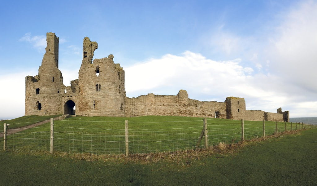 Dunstanburgh Castle and its structure with green surroundings.