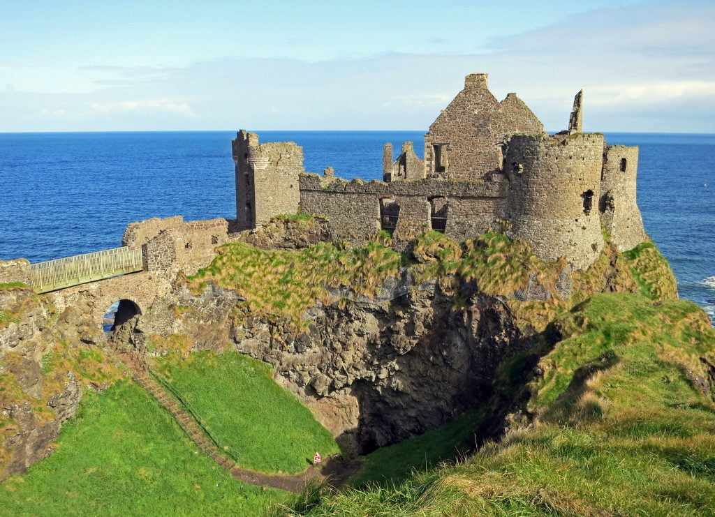 The picturesque view of Dunluce Castle on the clifftop by the sea.