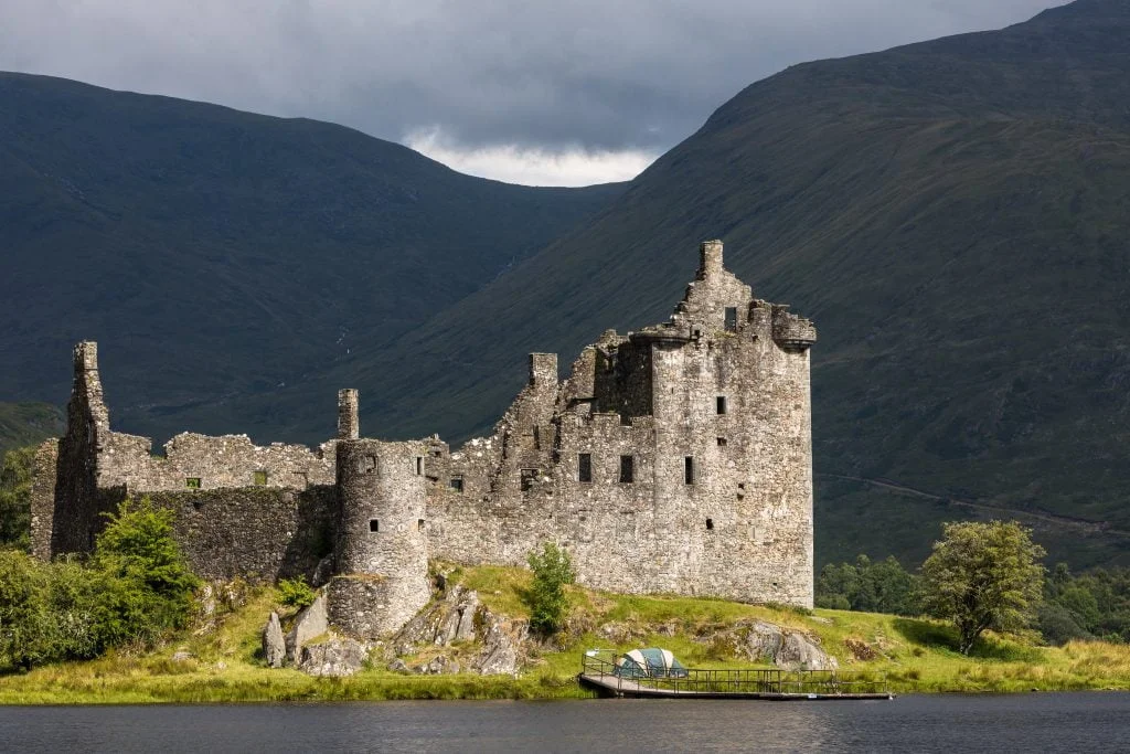 The scenic view of Kilchurn Castle near the water and the mountain behind.