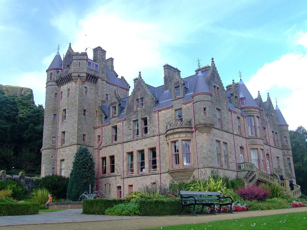 top 10 castles to visit in ireland The beautiful Belfast Castle in front of the garden's fountain.