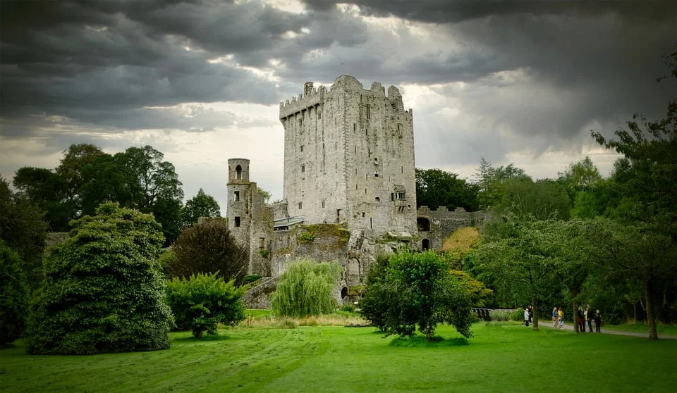 The tower of Blarney Castle surrounded by trees with view visiting tourists spotted. 