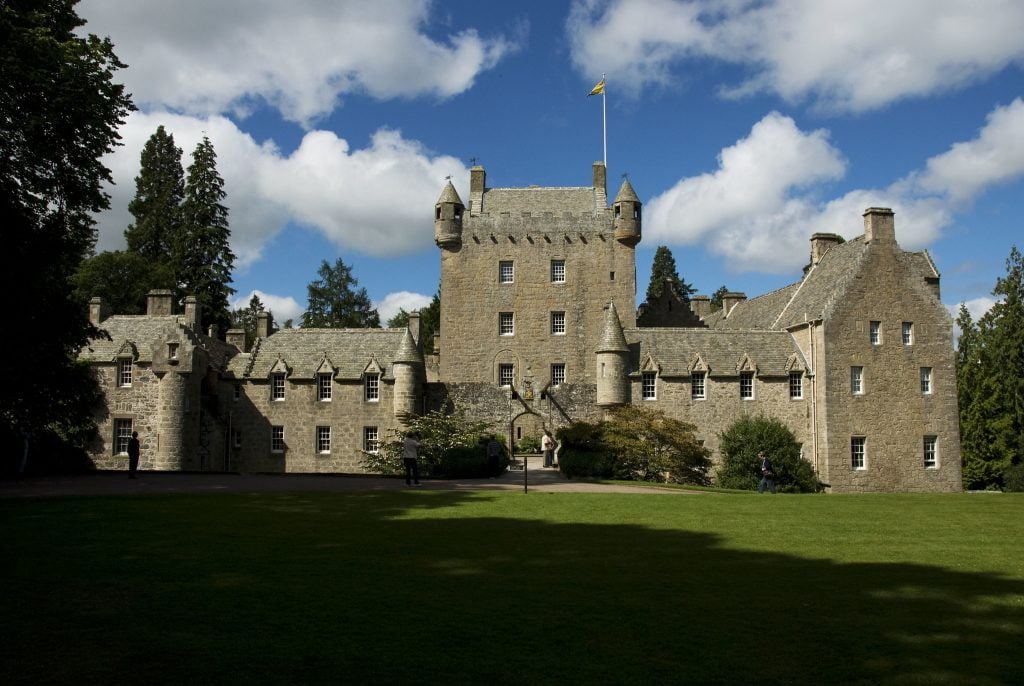 The front view of Cawdor Castle where you can see the green grasses and surrounded by trees. 