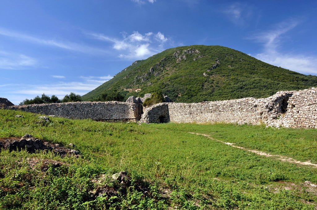 The walls of Gardiki Castle with a mountain view at the back.