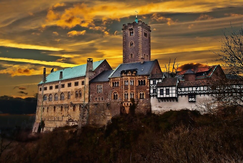 The picturesque view of Wartburg Castle under the orange skies.