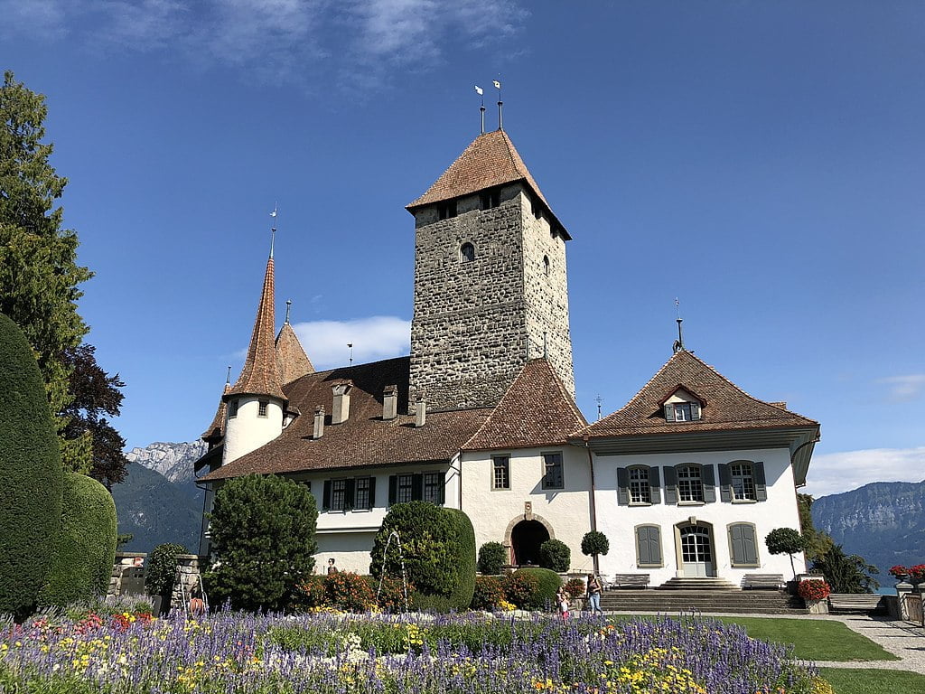 Spiez Castle view in front of the beautiful garden with blooming flowers.