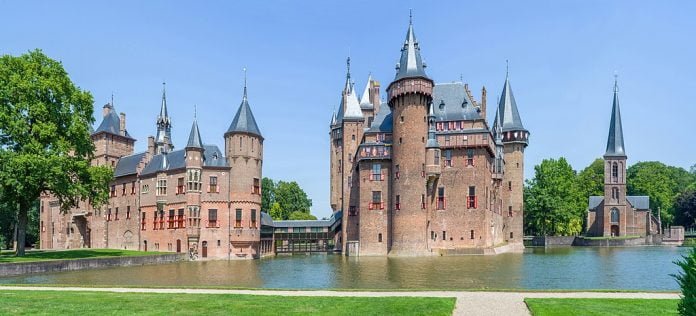 A stunning view of De Haar Castle from a distance surrounded by water.