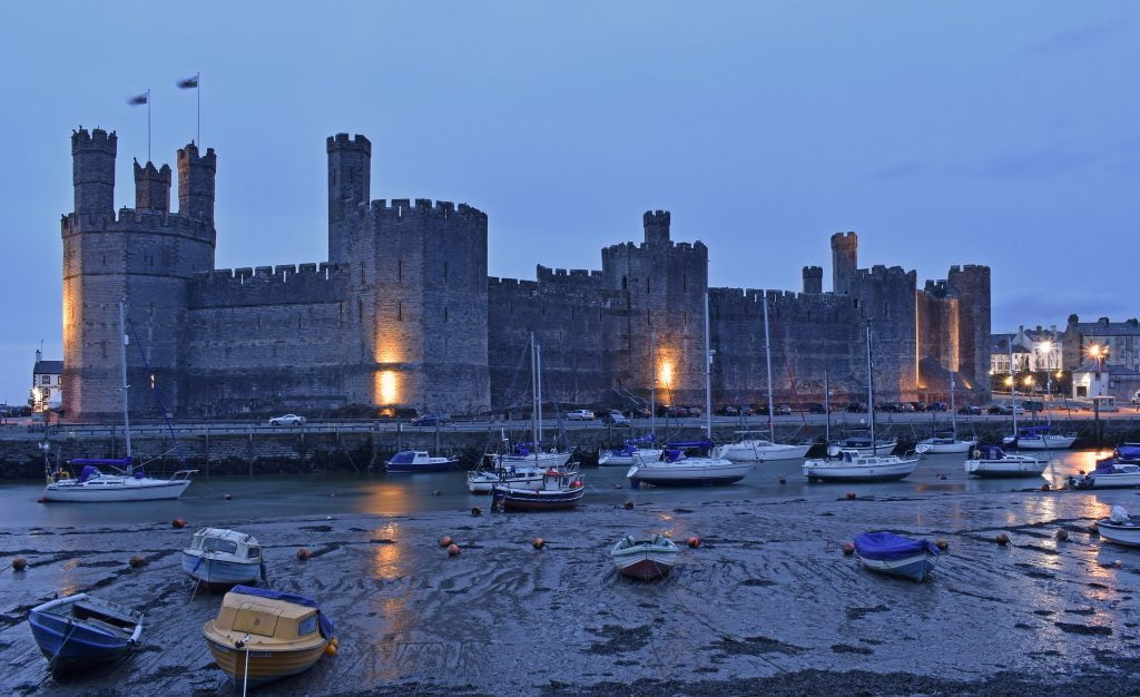 Carnarvon Castle a medieval fortress surrounded by boats.