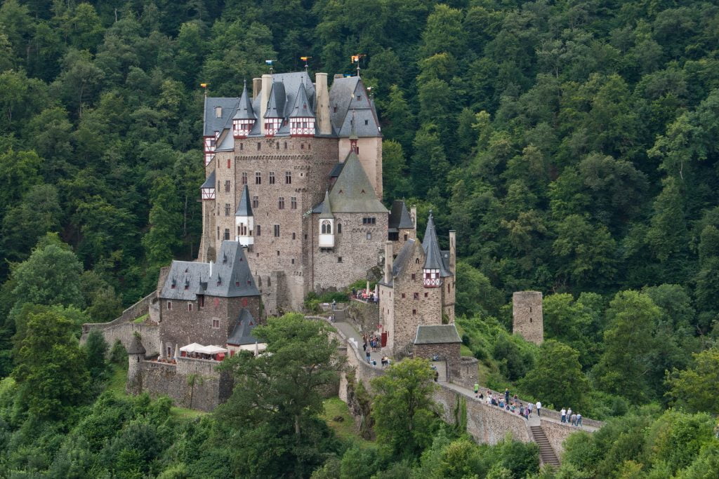 A panoramic view of Eltz Castle surrounded by greens.